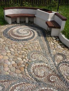 a bench sitting on top of a stone floor next to a garden area with rocks