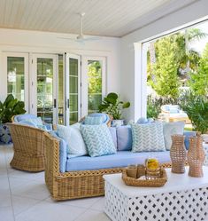 a living room with wicker furniture and blue cushions on the couches in front of glass doors