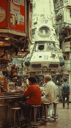 two people sitting at a bar in front of a space shuttle