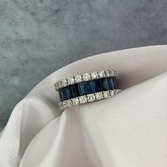 a diamond and sapphire ring sitting on top of a white cloth