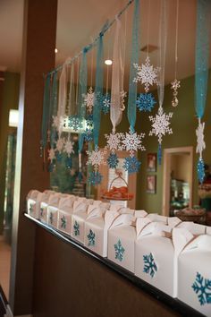 snowflakes are hanging from the ceiling in front of a store window with blue ribbon