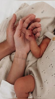 a person holding a baby's hand on top of a blanket