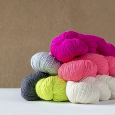 several skeins of yarn sitting on top of a white table next to a brown wall