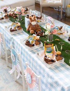 a table topped with lots of cupcakes and teddy bears on top of grass