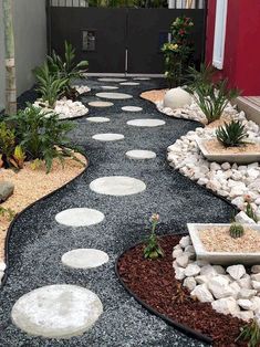 a walkway made out of rocks and gravel with plants on each side in the middle