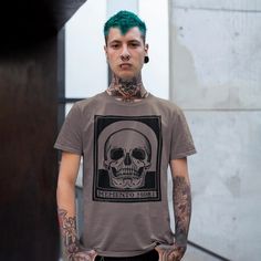 a man with green hair and tattoos wearing a t - shirt that has a skull on it