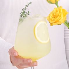 a person holding a glass with lemonade and flowers in it