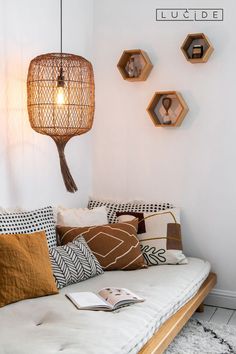 a bed with pillows and some lights hanging from the headboard on the wall above it