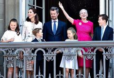 a group of people standing on top of a balcony next to each other with their arms in the air