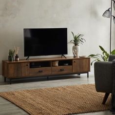 a flat screen tv sitting on top of a wooden entertainment center in a living room