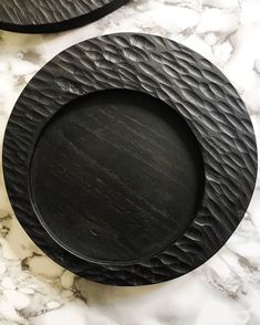 two black plates sitting on top of a marble counter