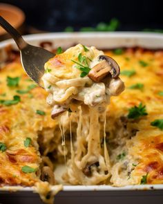 a close up of a casserole dish with cheese and mushrooms being lifted from the casserole