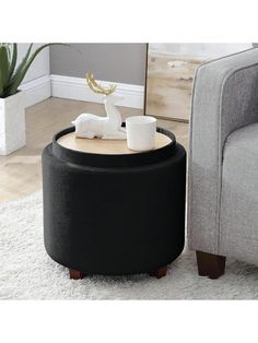 a black ottoman with a white deer figurine on top