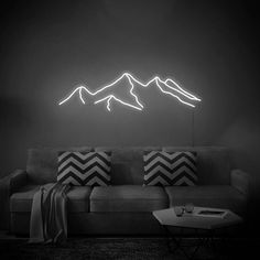 a black and white photo of a living room with mountains on the wall behind it