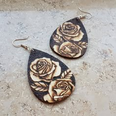 two wooden earrings with roses painted on them