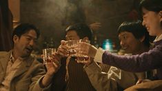 three men and one woman are toasting with wine glasses in front of each other