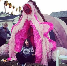 a woman sitting in front of a pink tent