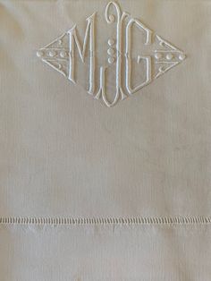 the monogrammed pillowcase is made from natural linen and has an embroidered design on it