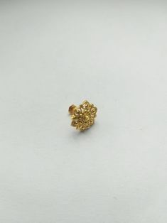 a small gold flower on a white surface with the top bead off and bottom bead down