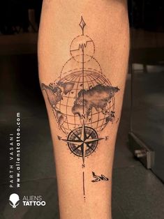 a man's leg with a compass and world map tattoo on the calf area