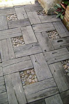 a wooden walkway with rocks and gravel in the ground next to a planter filled with potted plants