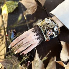 Indulge in the allure of our Vintage-Inspired Cowhide Leather Cuff Bracelet. Crafted on an 8 cm wide cowhide leather base, this unique piece features rustic wooden buttons, Gemstone Cross earthy tones embellished with high quality agate beads, rhinestones rustic wood buttons, vintage lace,  Swarovski stones, and a vibrant brown lace border for a touch of exotic elegance. This cuff is a testament to meticulous craftsmanship, adding a vintage flair to your style.  Embrace the joy of gifting or tre Handmade Adjustable Bracelet For Accessorizing, Adjustable Handmade Bracelets, Handmade Steampunk Bracelets As Gift, Handmade Steampunk Bracelets For Gift, Black Wearable Art Bracelet, One Of A Kind Bangle Bracelet, Wearable Art Style, Handmade Wearable Art Bracelets For Party, Vintage Hand Wrapped Wrap Bracelet For Gift, Handmade Wearable Art Bracelet For Party