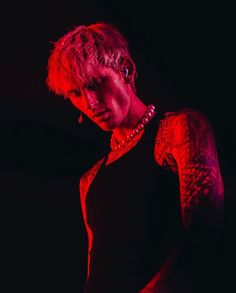 a man with tattoos on his arm and chest standing in front of a black background