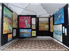 a room with paintings on the walls and carpeted flooring in front of it