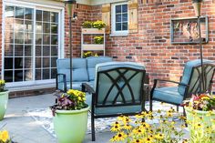 some chairs and flowers in front of a brick building with glass doors that lead to the patio