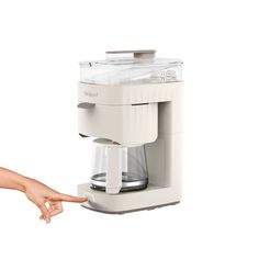 a person is pressing the button on a small coffee maker that's attached to a wall