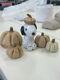 a dog figurine sitting on top of a table next to small pumpkins