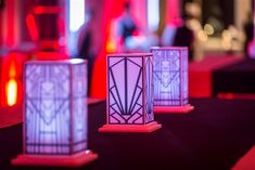 three lit candles sitting on top of a table next to each other in front of a red light