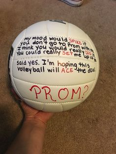 a hand holding a white volleyball with words written on it