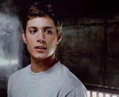 a young man standing in front of a wall with lights on it's sides