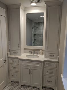 a bathroom with white cabinets and a large mirror