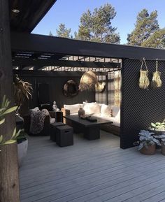 an outdoor living area with couches, tables and potted plants on the deck