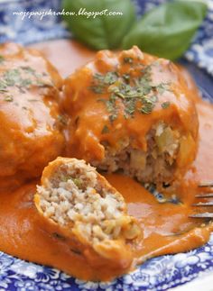 two meatballs covered in gravy on a blue and white plate with a fork