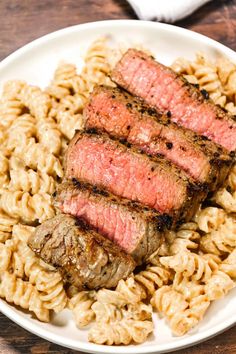 steak and macaroni on a white plate with a wooden table in the background