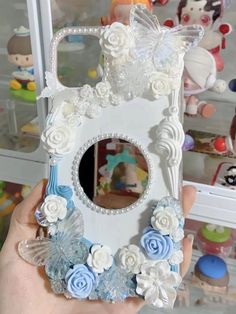 a hand holding up a white and blue case with flowers on it's sides