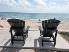 two lawn chairs facing the beach on a sunny day