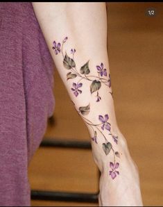 a woman's foot with purple flowers and leaves on her left side, tattoo style