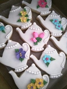 decorated cookies in the shape of teapots and flowers on a tray with white icing