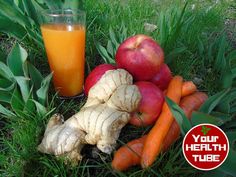 carrots, apples, and ginger are on the grass next to an orange juice