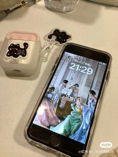 a cell phone sitting on top of a table next to a couple of figurines