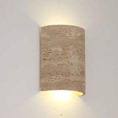 A Natural Travertine Art Deco Wall Lamp from Morsale.com, crafted from beige, porous stone and shaped into a cylinder, is mounted on a white wall. The light radiates softly from both the top and bottom, generating an ambient glow around the fixture that accentuates its ART DECO design. Wood Wall Lights, Vintage Bedroom Decor, Stone Lamp, Natural Stone Wall, Pendant Lighting Dining Room, Dining Room Light Fixtures, Deco Wall, Art Deco Wall, Wall Lamps Bedroom