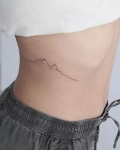 a woman's stomach with a small wave tattoo on her lower side ribcage