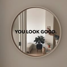 a round mirror with the words you look good in black on it and a person taking a photo