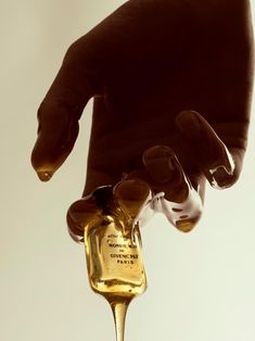 a hand holding an oil bottle with liquid coming out of it and dripping from the top