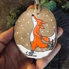 a hand holding a wooden ornament with an image of a fox on it