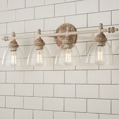 a bathroom light fixture with five clear glass shades hanging from a brick wall behind it